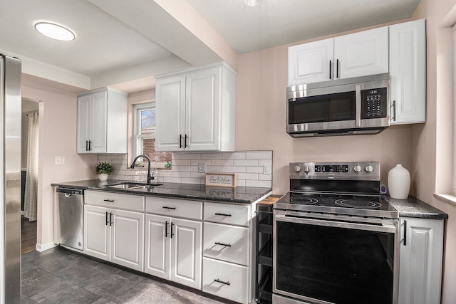 kitchen featuring stainless steel appliances, a sink, white cabinetry, tasteful backsplash, and dark stone countertops