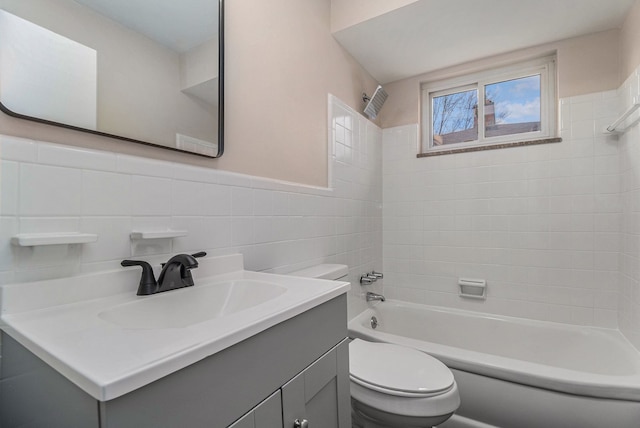 bathroom with toilet, a wainscoted wall, bathtub / shower combination, vanity, and tile walls