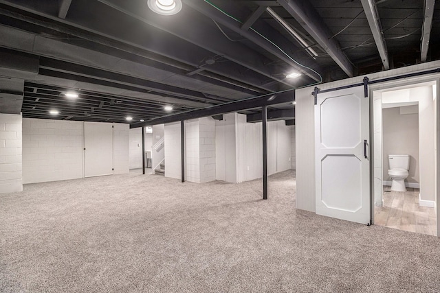 finished basement with carpet floors, a barn door, and stairway