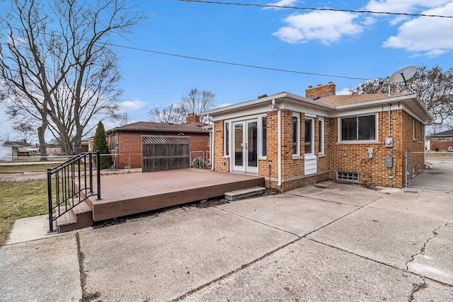 rear view of property featuring french doors, a chimney, fence, a wooden deck, and brick siding