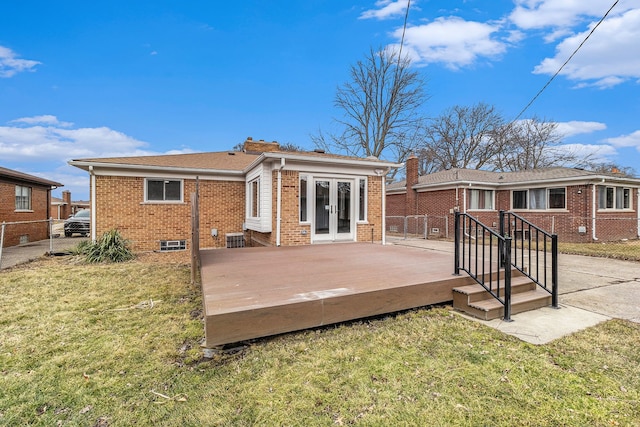 rear view of property with french doors, brick siding, a yard, and fence