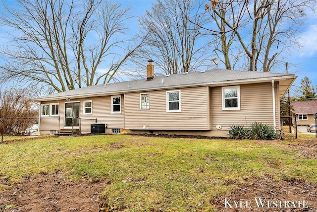 back of property featuring entry steps, central AC unit, fence, a lawn, and a chimney