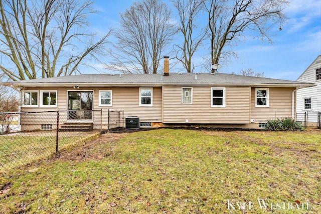 rear view of house with a chimney, fence, central AC, and a yard