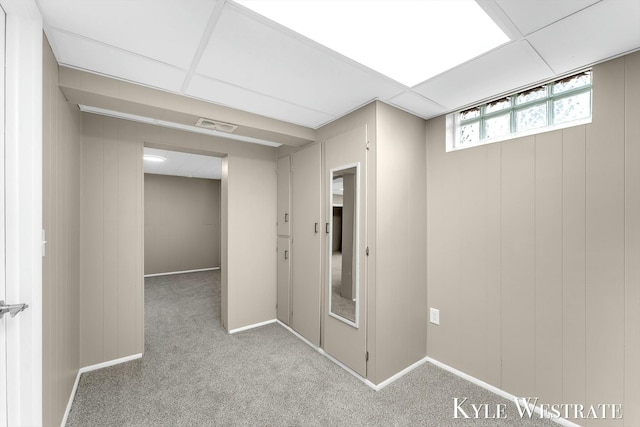 basement with baseboards, visible vents, a drop ceiling, and carpet flooring