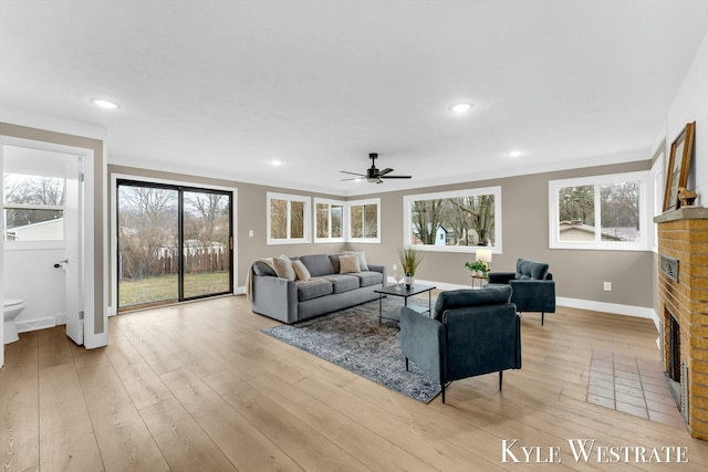 living area featuring recessed lighting, baseboards, a fireplace, and light wood finished floors