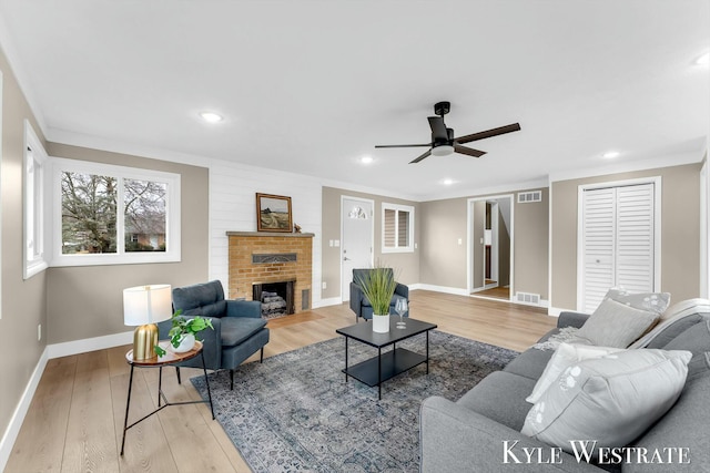 living room with light wood-style flooring, a fireplace, and visible vents