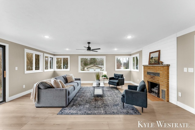 living area featuring light wood-style flooring, recessed lighting, a fireplace, a ceiling fan, and baseboards