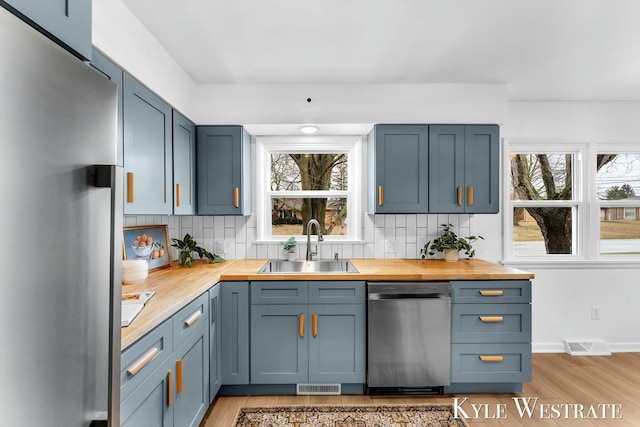 bar featuring visible vents, appliances with stainless steel finishes, backsplash, and a sink