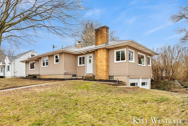 rear view of house with a garage, entry steps, a yard, and a chimney