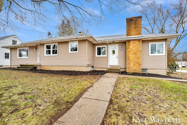 view of front of property with entry steps, a chimney, and a front yard