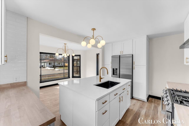 kitchen featuring appliances with stainless steel finishes, a sink, white cabinets, and light wood-style floors