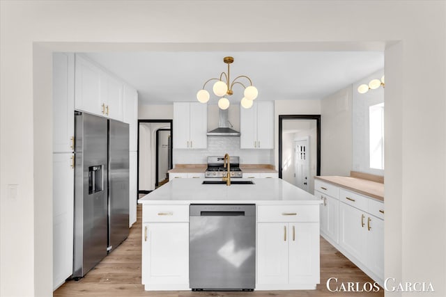 kitchen featuring stainless steel appliances, white cabinetry, light countertops, backsplash, and wall chimney exhaust hood