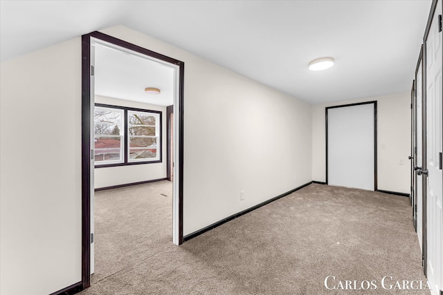 unfurnished bedroom featuring carpet, lofted ceiling, and baseboards