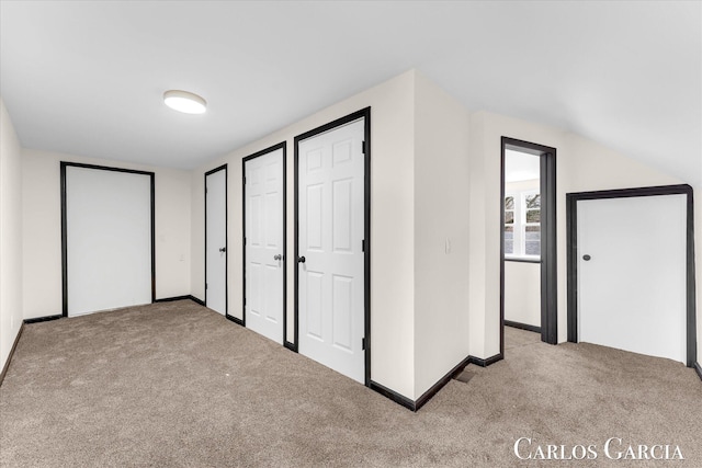 unfurnished bedroom with two closets, baseboards, and carpet flooring