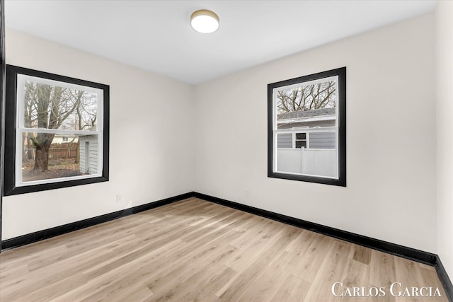 spare room with baseboards and wood finished floors