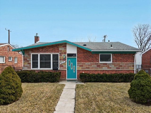 view of front of property with brick siding, a chimney, a front yard, and a shingled roof