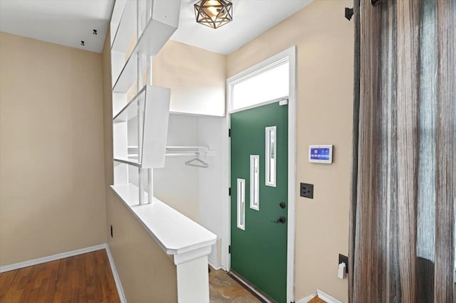 entryway featuring elevator, baseboards, and wood finished floors