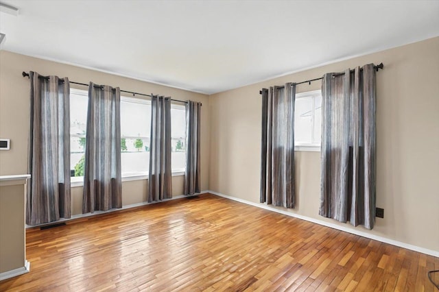 empty room featuring baseboards, visible vents, and hardwood / wood-style floors