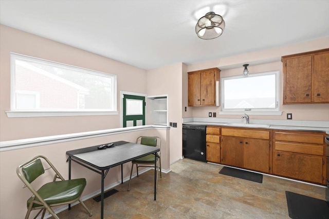 kitchen with black dishwasher, brown cabinetry, and a sink