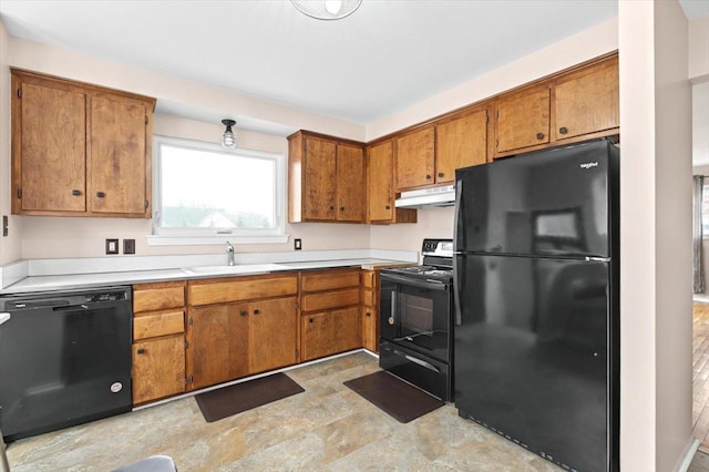 kitchen featuring brown cabinetry, under cabinet range hood, light countertops, black appliances, and a sink