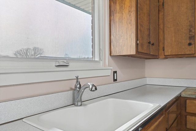 kitchen featuring light countertops, brown cabinets, and a sink