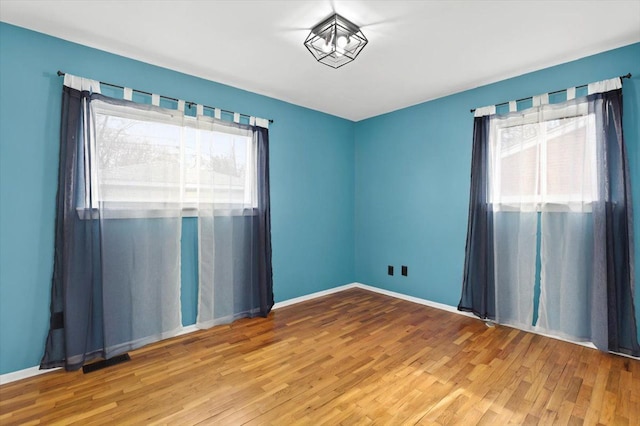 empty room featuring visible vents, baseboards, and wood finished floors