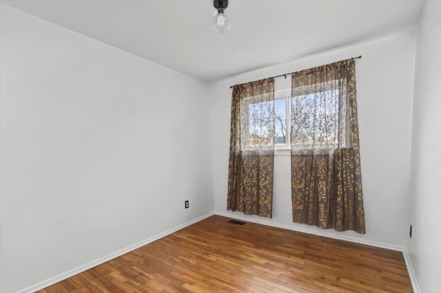 unfurnished room with hardwood / wood-style flooring, baseboards, and visible vents