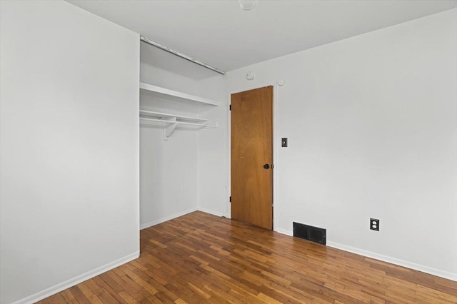 unfurnished bedroom with baseboards, a closet, visible vents, and wood finished floors