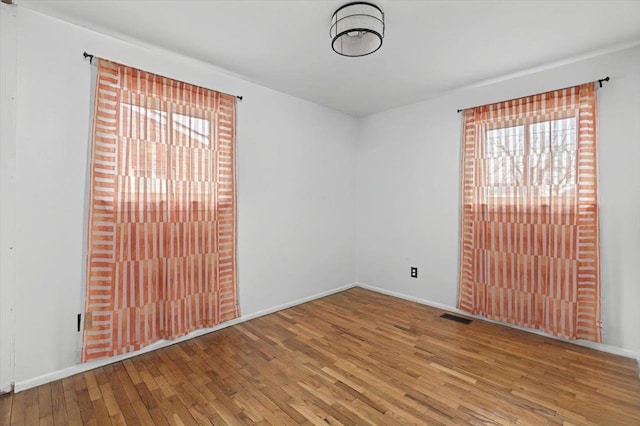 interior space with wood-type flooring, visible vents, and baseboards