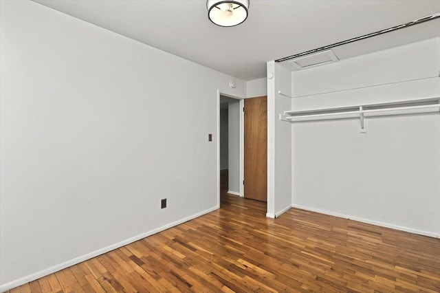 unfurnished bedroom with a closet, wood-type flooring, and baseboards