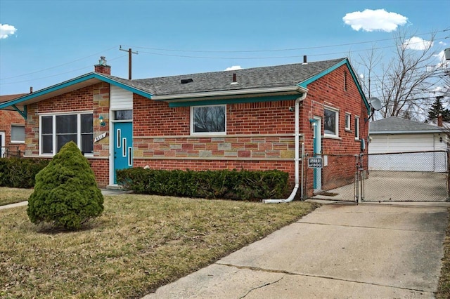 view of front facade with brick siding, a detached garage, an outbuilding, a gate, and a front yard