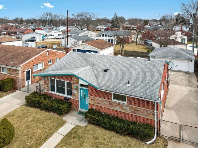 view of front of property with a residential view, brick siding, fence, and roof with shingles