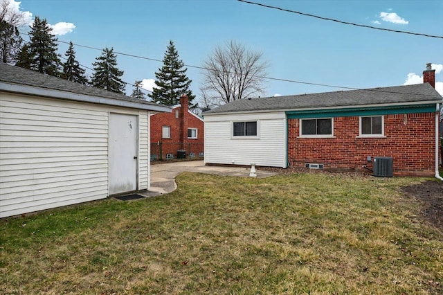 rear view of house featuring a patio, a chimney, cooling unit, a yard, and brick siding