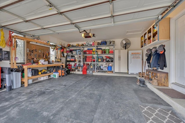 garage with a garage door opener, freestanding refrigerator, and a workshop area