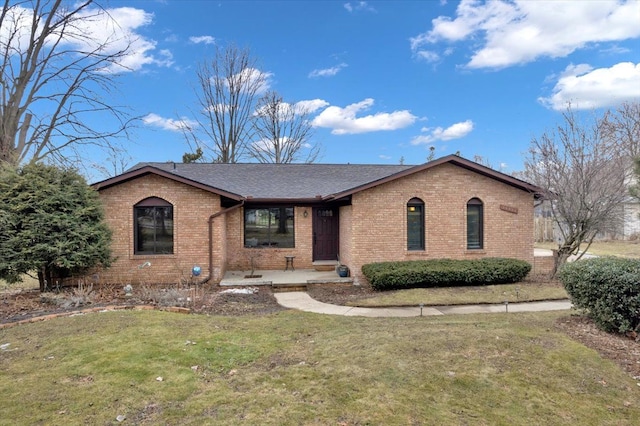 view of front of home with a front yard, brick siding, and roof with shingles