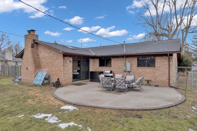 rear view of property with a yard, brick siding, a patio, and fence