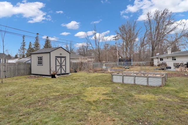 view of yard featuring a storage shed, a fenced backyard, a vegetable garden, and an outbuilding