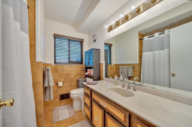 full bathroom with toilet, vanity, visible vents, tile walls, and tile patterned floors