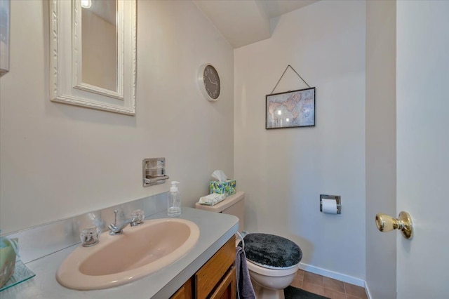 half bathroom featuring baseboards, vanity, toilet, and tile patterned floors