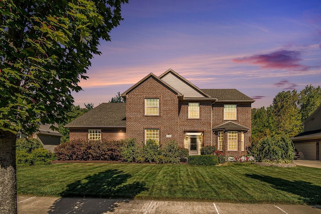 view of front of house featuring a garage, driveway, brick siding, and a front yard