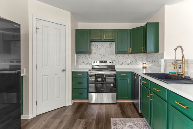 kitchen with green cabinetry, stainless steel appliances, light countertops, and a sink