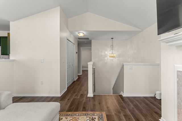 corridor featuring visible vents, baseboards, lofted ceiling, dark wood-type flooring, and an upstairs landing