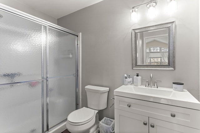 bathroom featuring vanity, a shower stall, and toilet