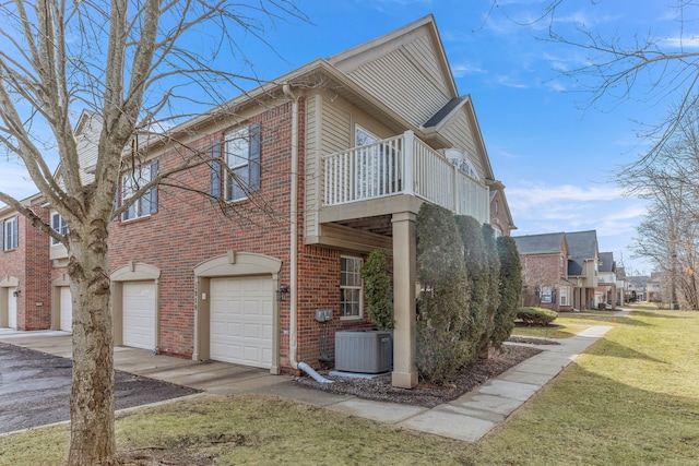 view of side of property with brick siding, central AC, driveway, a yard, and an attached garage