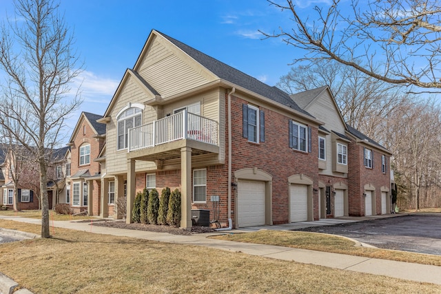 view of front of property with brick siding, a residential view, driveway, a balcony, and an attached garage