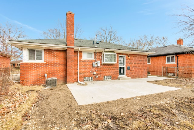 rear view of property featuring brick siding, fence, central air condition unit, a chimney, and a patio area