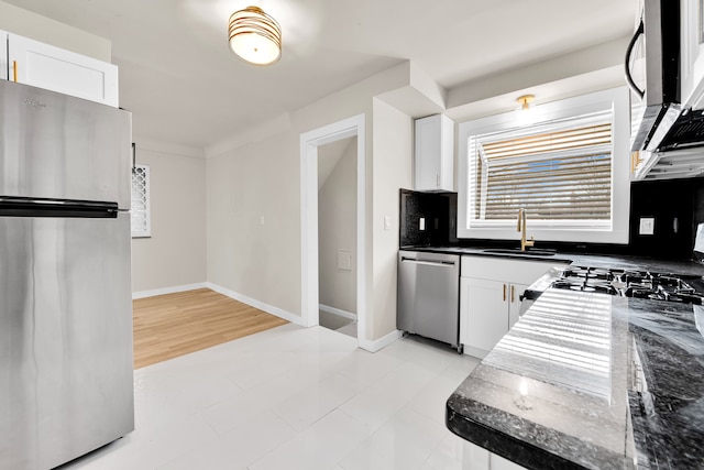 kitchen featuring white cabinets, appliances with stainless steel finishes, baseboards, and a sink