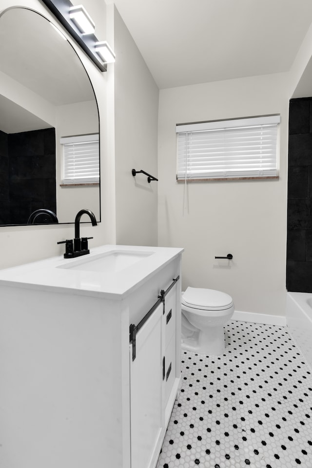 full bath featuring toilet, vanity, and baseboards