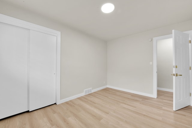 unfurnished bedroom with a closet, visible vents, light wood-style flooring, and baseboards