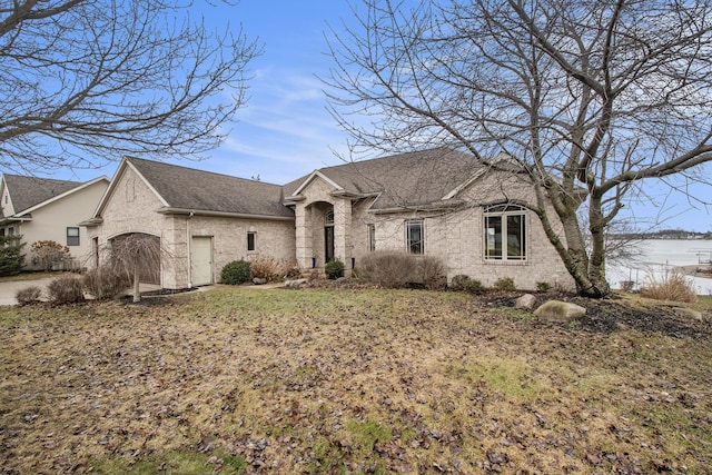 french country home with brick siding and a shingled roof